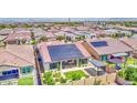 Aerial view of a home with solar panels, landscaped backyard with covered patio, and desert landscaping with many nearby houses at 10715 E Thornton Ave, Mesa, AZ 85212