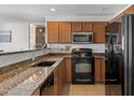 Well-lit kitchen with wood cabinets, granite countertops, and black appliances at 1350 S Greenfield Rd # 2133, Mesa, AZ 85206