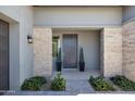 A stylish modern front entryway with a stone facade, a dark wood door, and neat landscaping at 17183 W San Marcos St, Surprise, AZ 85388