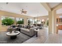 Open-concept living area featuring tile floors, ceiling fan, a comfortable gray couch, and a dining area at 19803 N Desert Song Ct, Surprise, AZ 85374