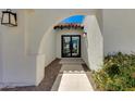 Close up on the entryway of a modern home with an arched walkway and black framed glass door at 7328 E Laredo Ln, Scottsdale, AZ 85250