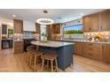 Modern kitchen featuring wood cabinets, geometric backsplash, black appliances, and an island with seating at 7328 E Laredo Ln, Scottsdale, AZ 85250