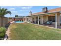 Spacious backyard featuring a well-maintained lawn, covered patio, BBQ, and sparkling in-ground pool at 7649 W Dahlia Dr, Peoria, AZ 85381
