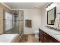 Bathroom featuring a modern vanity, a framed shower with glass doors, and a soaking tub at 7649 W Dahlia Dr, Peoria, AZ 85381