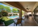 A relaxing covered patio offering views of the pool, waterfall, and lush landscaping at 8036 E Mercer Ln, Scottsdale, AZ 85260