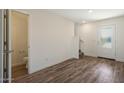 Open-concept area showcasing wood-look flooring, access to a half-bath, and entry to upper level at 1091 W West Virginia Ave, Florence, AZ 85132