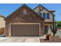 Home exterior featuring a two-car garage and stone facade with desert landscaping at 14895 W Jenan Dr, Surprise, AZ 85379