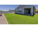 Well-maintained backyard featuring artificial grass, a covered patio, and block wall fencing at 17704 W Fetlock Trl, Surprise, AZ 85387