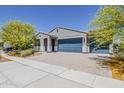 Single-story home with blue garage doors, desert landscaping, and paved driveway at 17704 W Fetlock Trl, Surprise, AZ 85387