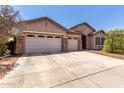 Lovely home exterior featuring a three-car garage, stone accents and a welcoming entrance at 1955 E Grand Canyon Dr, Chandler, AZ 85249