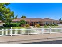 Well-maintained home exterior with lush green lawn, mature trees, and charming white picket fence at 3160 E Fox St, Mesa, AZ 85213