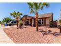 Inviting home featuring desert landscaping, mature palm trees, and a well-maintained lawn at 4110 W Villa Linda Dr, Glendale, AZ 85310