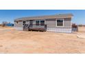 Single-story home with gray siding, covered porch, and desert surroundings at 52680 W Meadow Green Rd, Maricopa, AZ 85139