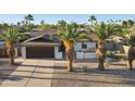 Inviting single-story home featuring desert landscaping, palm trees, and a long, paved driveway at 5802 E Spring Rd, Scottsdale, AZ 85254