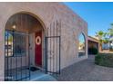Charming stucco house with a red front door, secure gated entrance, and desert landscaping at 6819 E Sheena Dr, Scottsdale, AZ 85254