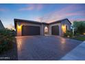 Home featuring a brick driveway, three-car garage and desert landscaping at 13236 W Montansoro Ln, Peoria, AZ 85383