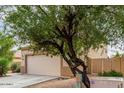 Street view of two-story house, showing the garage and some landscaping with a large tree at 13443 W Crocus Dr, Surprise, AZ 85379
