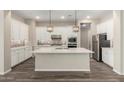 Bright kitchen featuring white cabinets, stainless steel appliances, an island with marble countertop, and pendant lighting at 14045 W Desert Flower Dr, Goodyear, AZ 85395