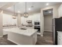 Bright kitchen featuring white cabinets, stainless steel appliances, an island with marble countertop, and pendant lighting at 14045 W Desert Flower Dr, Goodyear, AZ 85395
