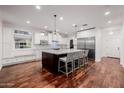 Bright kitchen boasts hardwood floors, stainless appliances, marble countertops, and a kitchen island with barstool seating at 4021 E Glenrosa Ave, Phoenix, AZ 85018