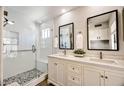 Bright bathroom featuring double sinks, white cabinets and a stand-up shower with stone tile floor at 4712 E Lone Cactus Dr, Phoenix, AZ 85050