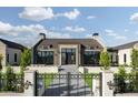 A modern home with a symmetrical facade, an iron gate, stone accents, and a well-manicured lawn at 4864 E Lafayette Blvd, Phoenix, AZ 85018