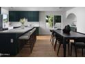 Beautiful kitchen featuring a large island, green cabinets, and a dining area with a black dining table and chairs at 5341 E Sheena Dr, Scottsdale, AZ 85254