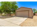 The property features a two-car garage with a spacious driveway and low maintenance desert landscaping at 8321 W Hughes Dr, Tolleson, AZ 85353
