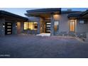 Contemporary home showcasing a brick driveway, stone accents, and modern multi-paneled front door at 9750 E Troon North Dr, Scottsdale, AZ 85262