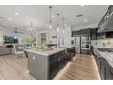 Island kitchen featuring modern appliances, a stylish sink, pendant lighting, and an open view to the living and dining area at 10127 E Tillman Ave, Mesa, AZ 85212
