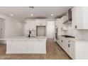 Bright, open-concept kitchen with white cabinets, stainless steel appliances, and large center island with a dark faucet at 21348 N Belt Dr, Maricopa, AZ 85138