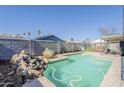 Inviting backyard pool with a rock waterfall feature, surrounded by a privacy fence and lush landscaping at 2202 W Enid Ave, Mesa, AZ 85202