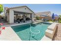 Inviting backyard with a sparkling pool, covered patio, outdoor seating, and lush landscaping for relaxation and entertaining at 24638 N 144Th Ave, Surprise, AZ 85387