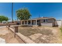 View of gray-painted single story house with mature shade tree in the front yard under clear blue sky at 5022 W Pierson St, Phoenix, AZ 85031