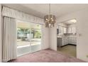 Dining room with sliding glass door, modern chandelier, and adjacent kitchen featuring white appliances at 6027 E Ellis St, Mesa, AZ 85204
