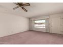 Bright living room showcasing carpet flooring, a ceiling fan, large windows and neutral paint at 6027 E Ellis St, Mesa, AZ 85204