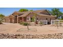 Single-story home featuring desert landscaping, white perimeter fencing, and a tan-colored exterior with stone accents at 9658 W Golddust Dr, Queen Creek, AZ 85144