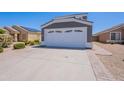 Front view of the house featuring the white two car garage, surrounded by desert landscape at 12801 W Sweetwater Ave, El Mirage, AZ 85335