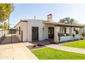 A charming single-story home featuring a red tile roof, a well-manicured lawn, and a secure gated driveway at 1309 W Lynwood St, Phoenix, AZ 85007