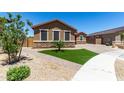 Well-maintained single-story home featuring stone accents, desert landscaping, and a charming green lawn at 15740 W Washington St, Goodyear, AZ 85338