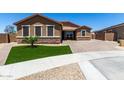 Charming single-story home with stone accents, green lawn, and a brick driveway at 15740 W Washington St, Goodyear, AZ 85338