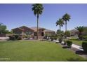 Inviting home with lush green lawn, mature palm trees, and a stone-detailed front entrance at 16386 W Papago St, Goodyear, AZ 85338