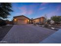 Warm home exterior featuring a large paved driveway and mature desert landscaping at 19334 W Pasadena Ave, Litchfield Park, AZ 85340