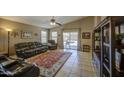 Cozy living room features leather furniture, a ceiling fan, tile flooring, and backyard access at 22333 E Calle De Flores St, Queen Creek, AZ 85142