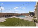 Relaxing backyard with a refreshing pool, patio with seating, string lights, and artificial turf area at 22812 N 123Rd Dr, Sun City West, AZ 85375