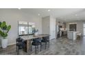 Stylish dining room with wood-look tile flooring, an adjacent modern kitchen, and stainless steel appliances at 38082 W Santa Barbara Ave, Maricopa, AZ 85138
