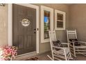 Inviting front porch with rocking chairs, a welcome sign on the door, and a pot of pink flowers at 4117 E Baylor Ln, Gilbert, AZ 85296