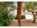 View of home with 2-car garage and manicured yard with desert landscaping and mature trees at 4738 N Greenview W Cir, Litchfield Park, AZ 85340