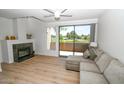 Bright living room with modern fireplace, wood floors, light-colored sofa, and sliding doors to the patio at 5122 E Shea Blvd # 1043, Scottsdale, AZ 85254