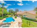 A serene backyard featuring a sparkling pool, stone patio, lush landscaping, and a view of the home's rear exterior at 7734 E Monica Dr, Scottsdale, AZ 85255